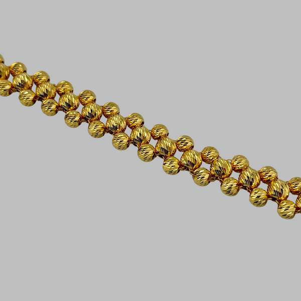 Gold beaded necklace on a light gray background