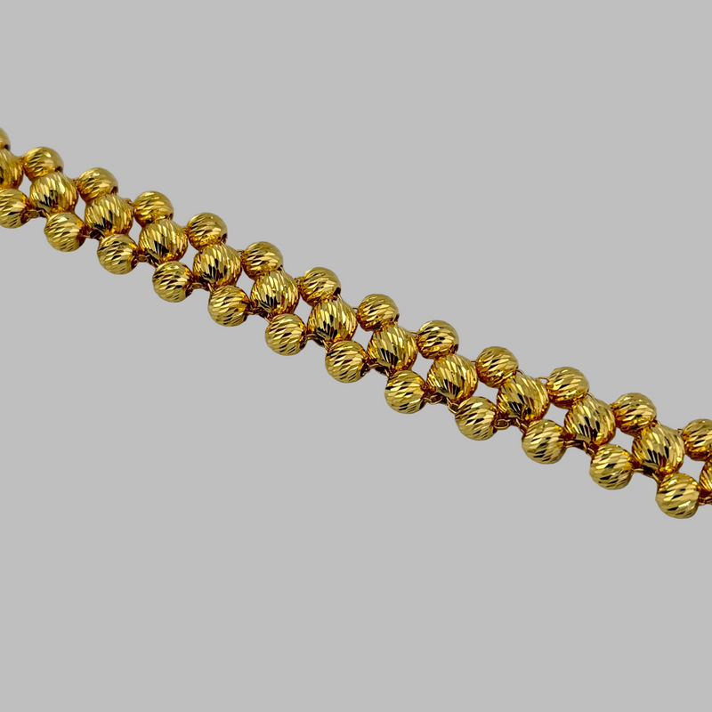 Gold beaded necklace on a light gray background